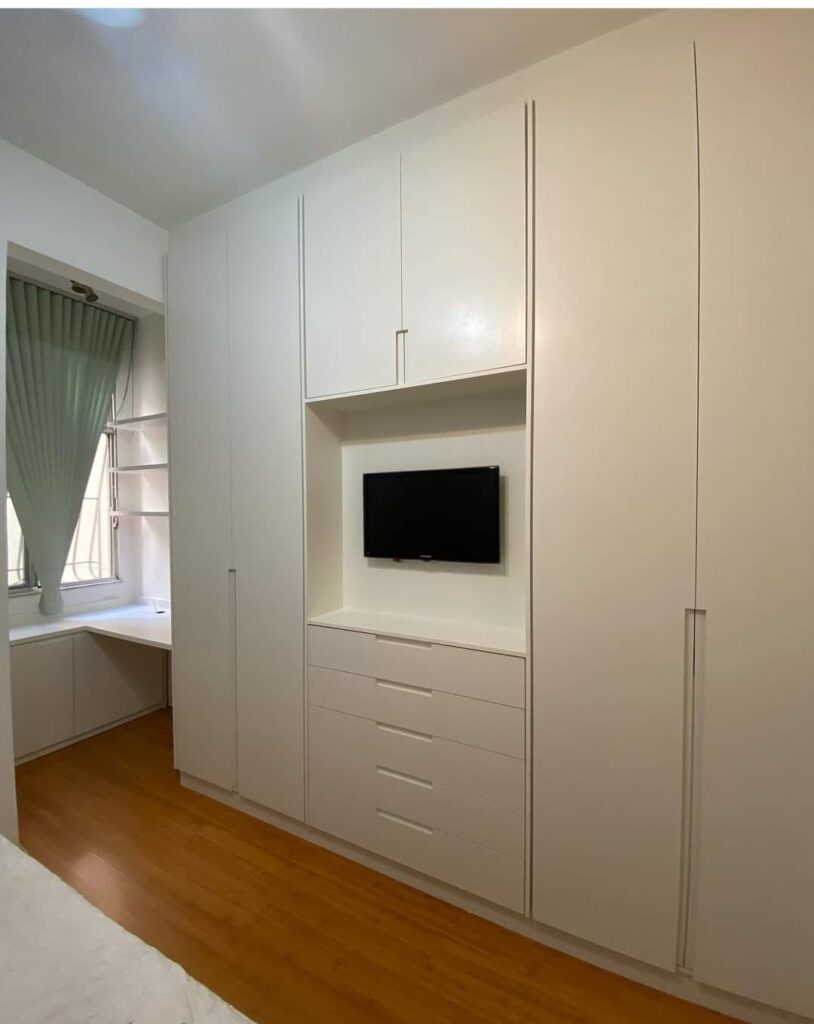 Guarda-roupa planejado de casal com design moderno, portas de correr e espaço central integrado para TV, combinando funcionalidade e elegância no quarto.